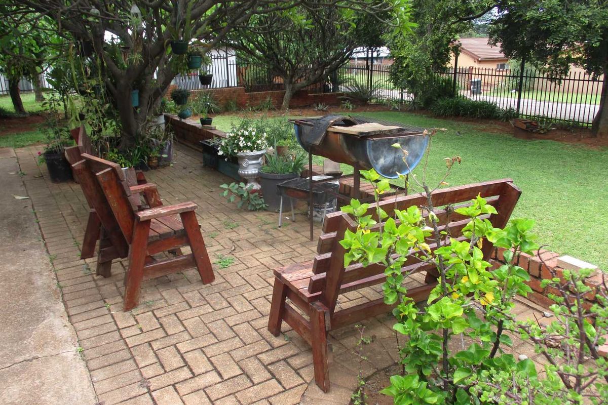 A paved outdoor patio area featuring a retaining wall and established garden surroundings, providing a functional space for outdoor relaxation.