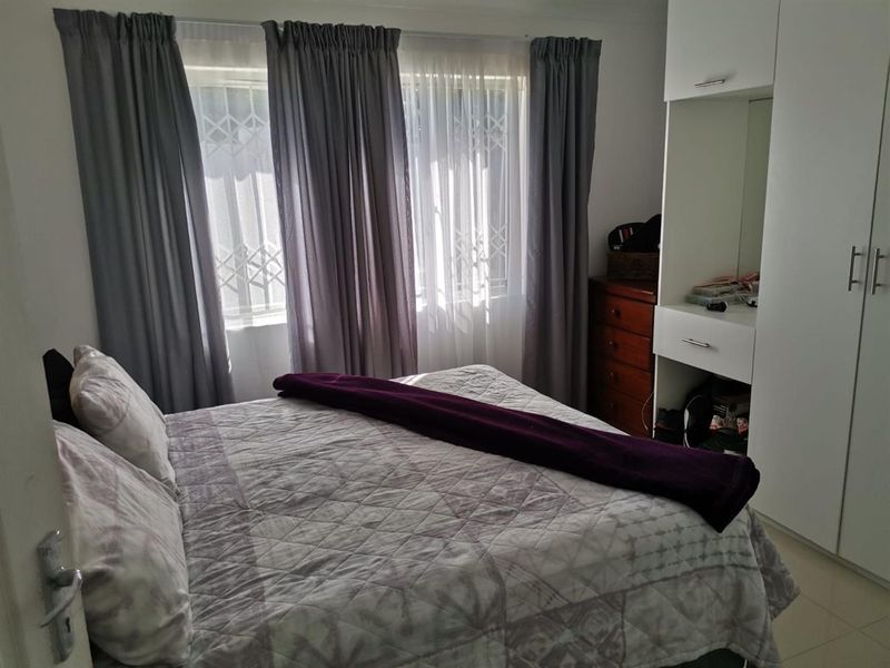 A well-maintained bedroom featuring built-in wardrobes, tiled flooring, and security gates on the windows, providing a functional and secure living space.