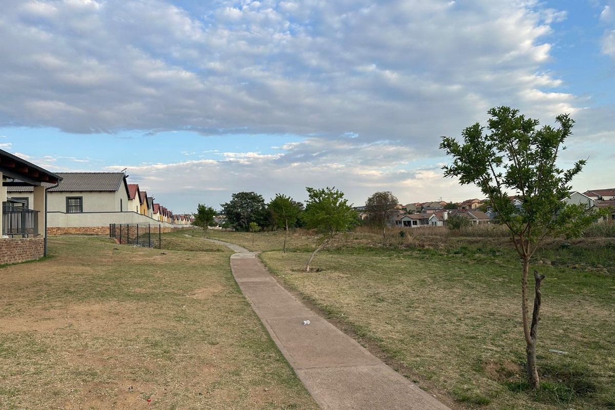 A view of the communal outdoor space and walking path within the residential estate, featuring landscaped grounds and surrounding apartment buildings.