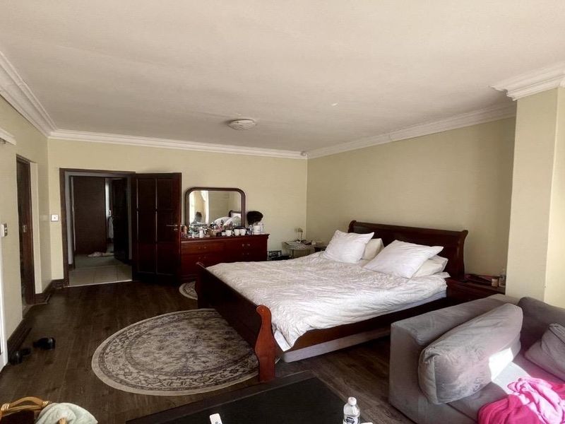 Spacious bedroom featuring laminate flooring, coving, and a built-in wardrobe with mirrored sliding doors.