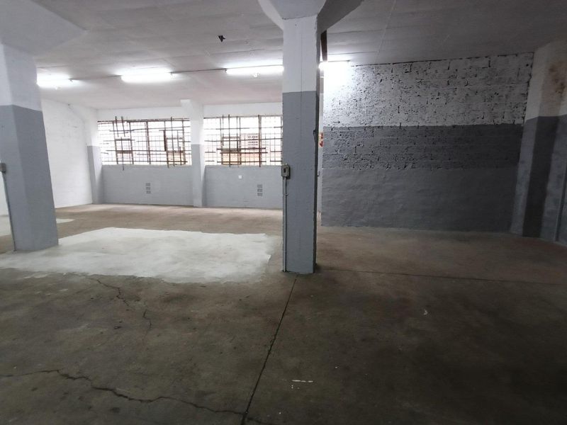 Spacious industrial utility area featuring concrete flooring, structural columns, and security-barred windows, suitable for storage or workshop use.
