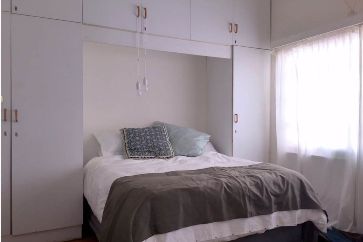 A bedroom featuring extensive built-in white cabinetry surrounding the bed area, providing ample integrated storage space and a bright, functional layout.