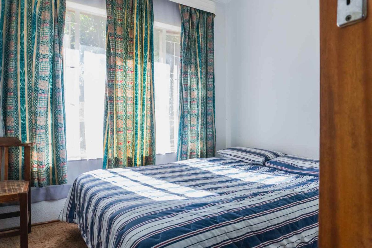 A bedroom featuring a large window that allows for natural light, complemented by carpet flooring.