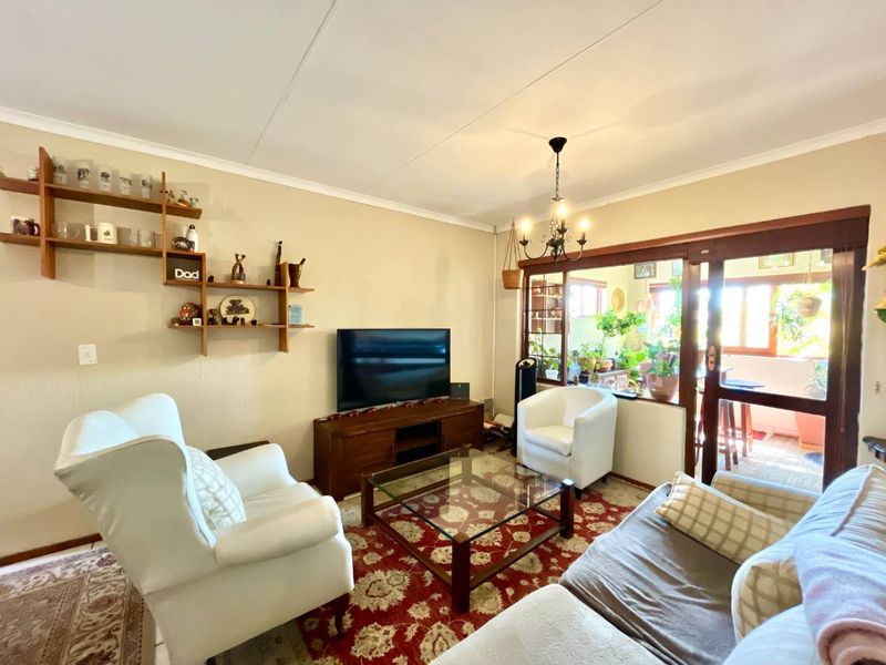 A comfortable living room featuring a coved ceiling, a central chandelier, and large sliding glass doors that provide access to an adjoining patio area.