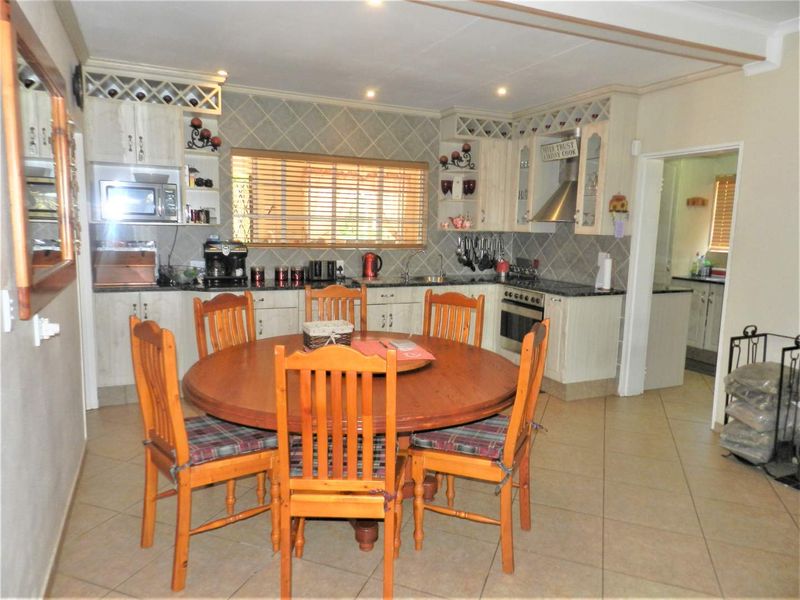 Open-plan kitchen and dining area featuring built-in cabinetry, granite countertops, integrated appliances, and tiled flooring, providing a functional space for cooking and dining.