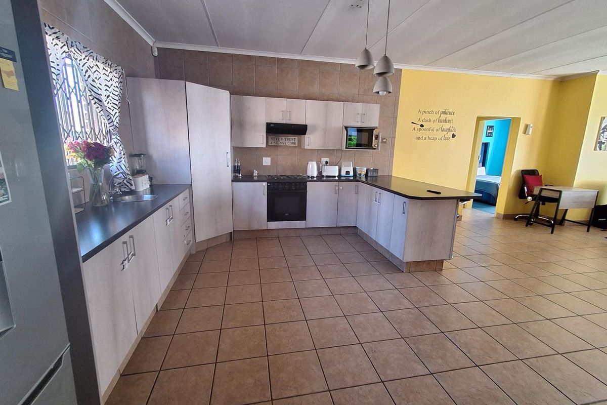 A functional kitchen featuring light-toned cabinetry, dark countertops, built-in appliances, and tiled flooring, offering a practical layout for daily cooking and meal preparation.