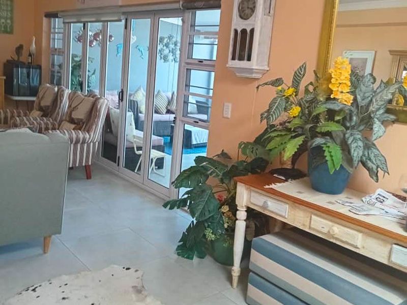A living room featuring tiled flooring and large aluminium sliding doors that provide access to an outdoor patio area.
