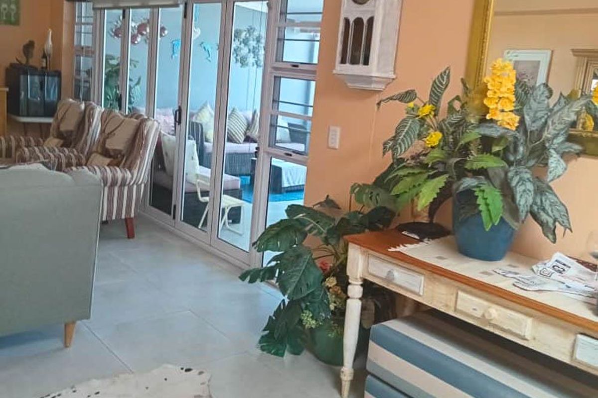 A living room featuring tiled flooring and large aluminium sliding doors that provide access to an outdoor patio area.