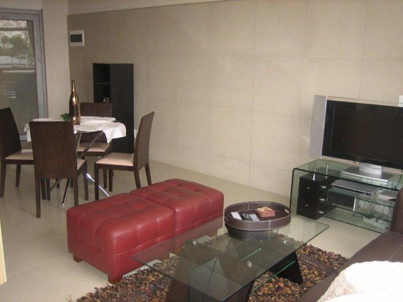 A living room area featuring large format wall tiles, neutral floor tiles, and a sliding glass door leading to an outdoor space.