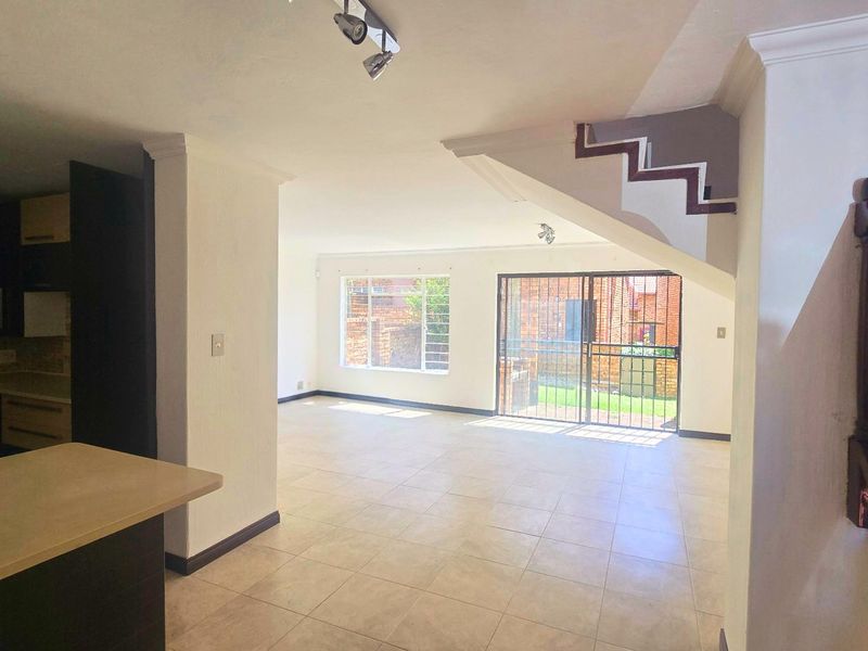 Spacious open-plan living area featuring tiled floors, a functional kitchen, and direct access to the rear garden through sliding glass doors.