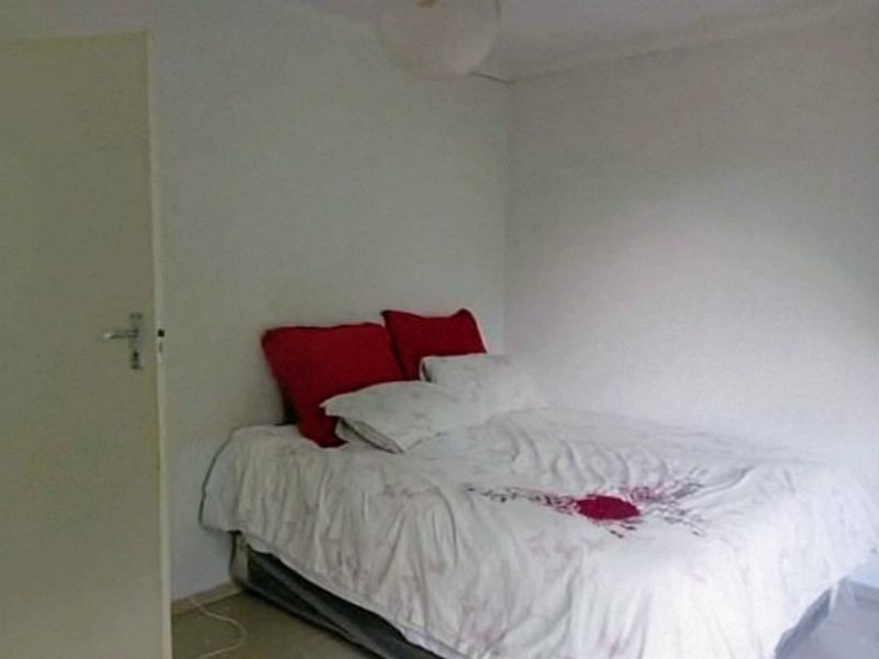 A simple bedroom featuring plain white walls and a standard internal door.
