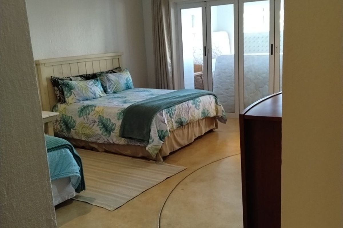 Spacious bedroom featuring polished concrete flooring and large sliding glass doors that provide ample natural light and access to the outdoor area.
