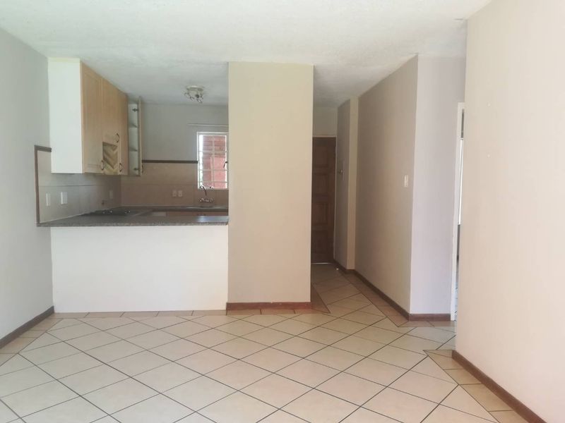 Open plan living area featuring tiled flooring and a functional kitchen with built-in cabinetry and granite countertops.