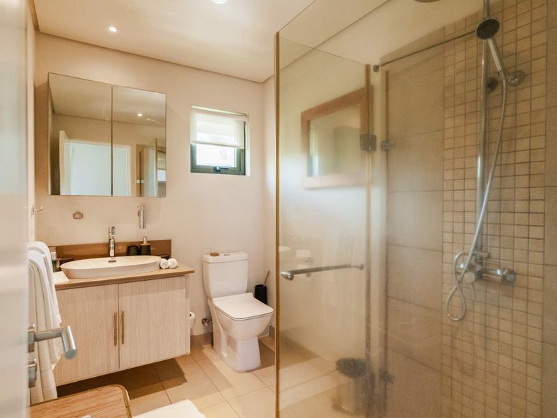 Modern bathroom featuring a glass-enclosed shower, vanity with vessel sink, mirrored medicine cabinet, and tiled flooring.