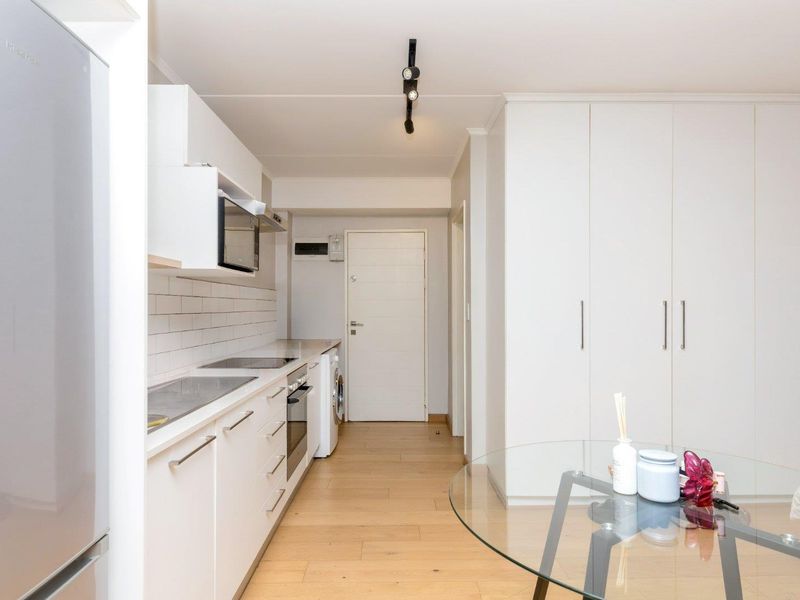 Modern kitchen featuring white cabinetry, subway tile backsplash, integrated appliances, and light wood-look flooring, offering a clean and functional cooking space.
