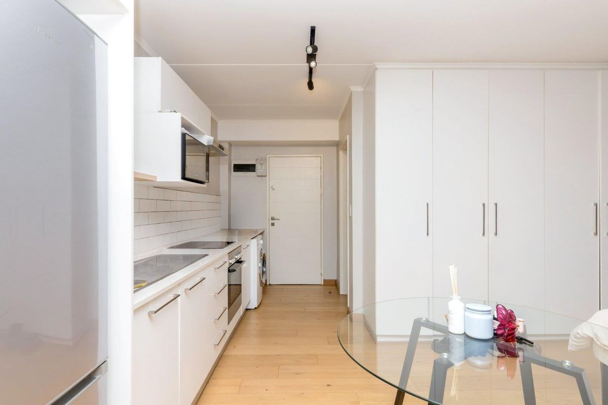 Modern kitchen featuring white cabinetry, subway tile backsplash, integrated appliances, and light wood-look flooring, offering a clean and functional cooking space.