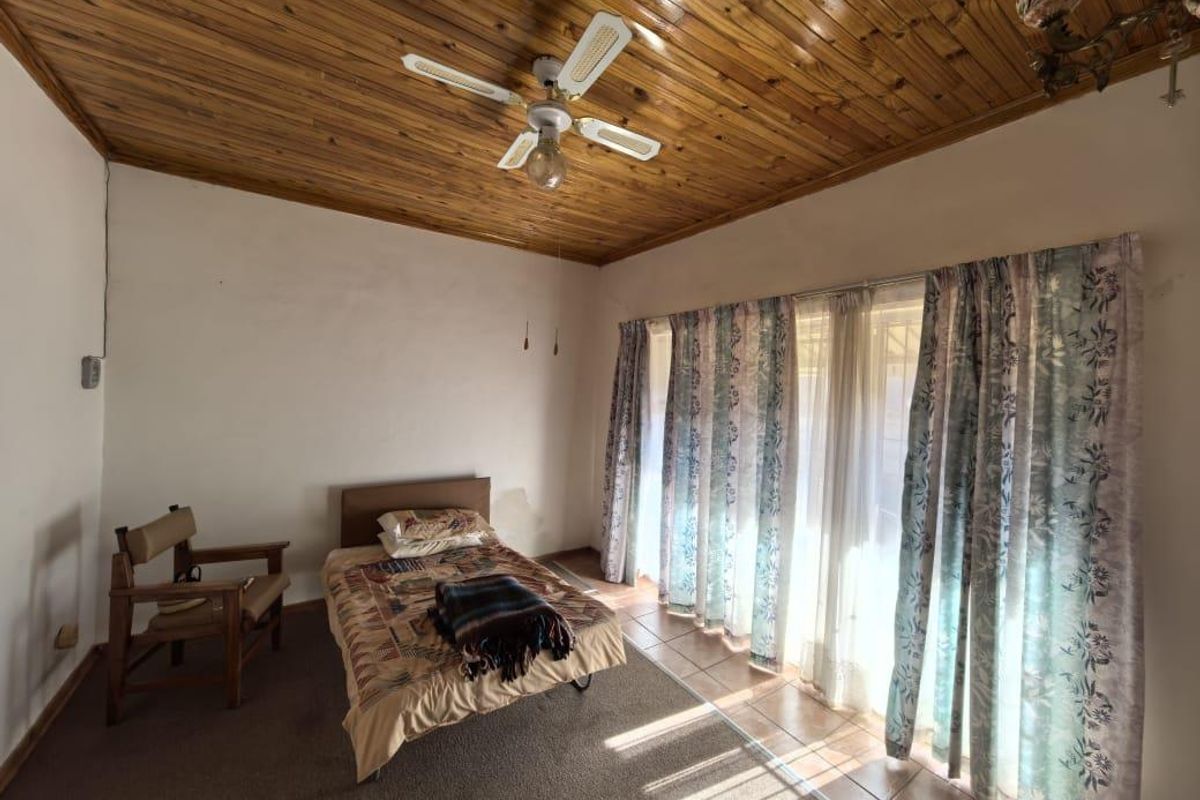A bedroom featuring a timber-clad ceiling, ceiling fan, and large sliding glass doors providing natural light and access to the exterior.