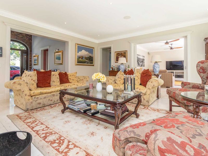 Spacious living room featuring elegant crown molding, recessed lighting, and polished tile flooring, with open transitions to adjacent living areas.