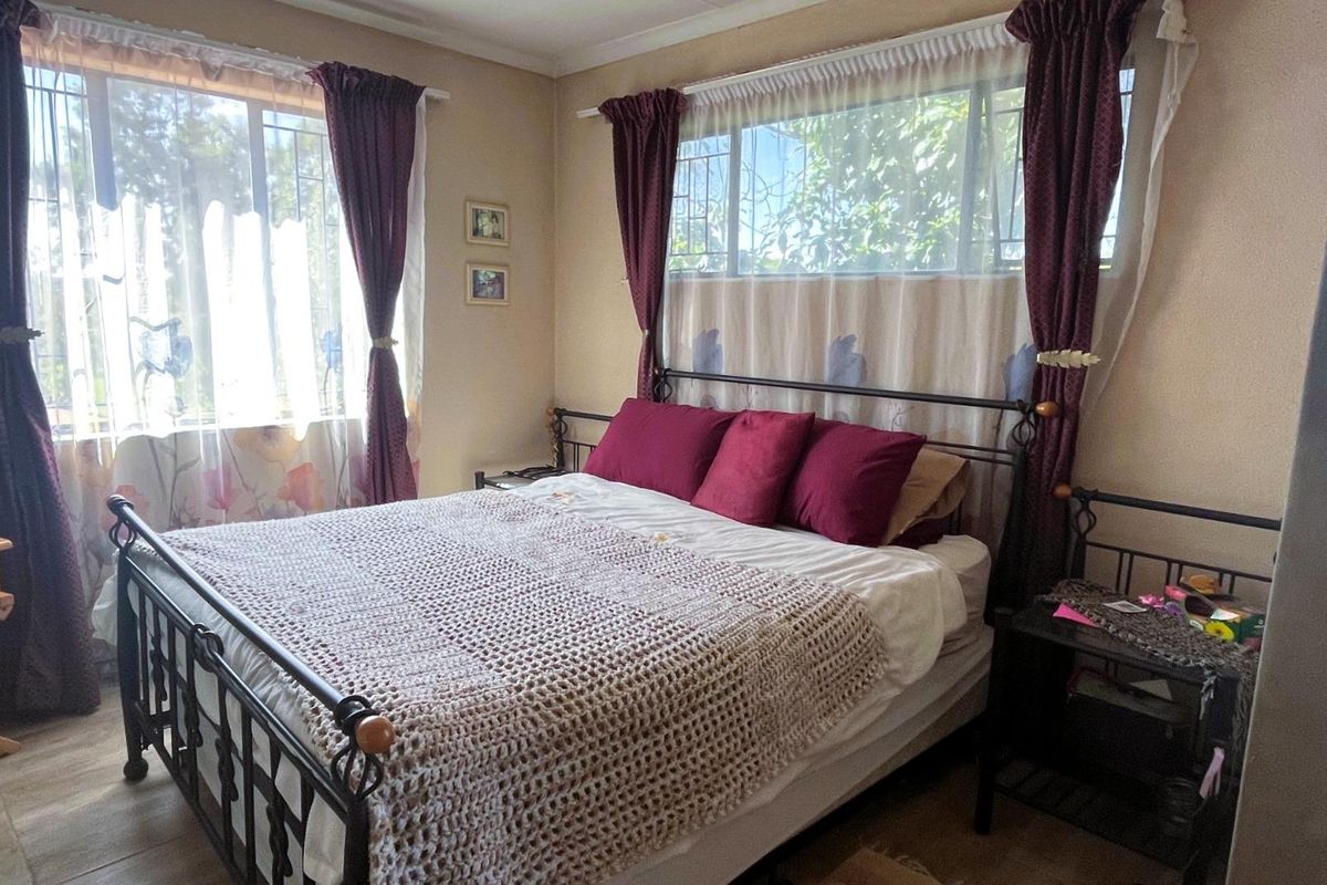A bedroom featuring tiled flooring and windows fitted with security bars, offering a functional and lived-in space.