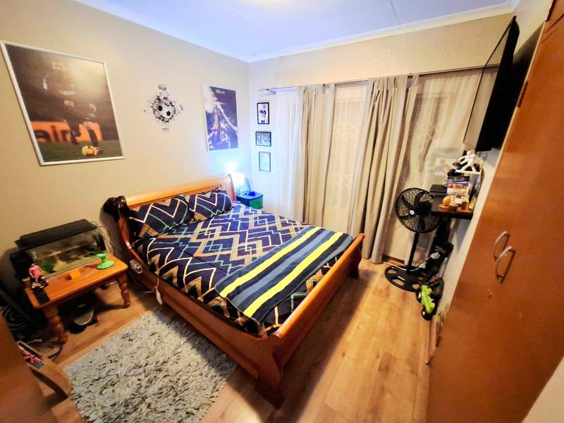 A functional bedroom featuring laminate flooring, a built-in wardrobe, and a sliding glass door providing access to the exterior.