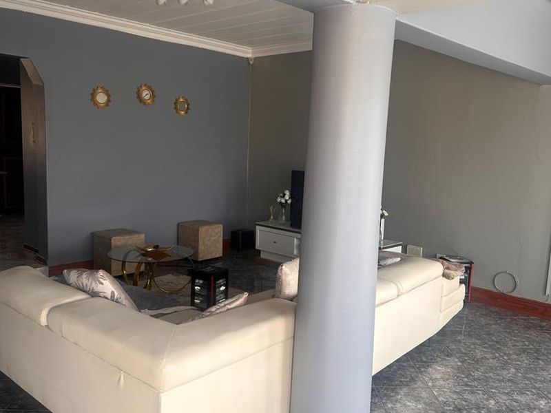 A spacious living area featuring tiled flooring, a prominent structural column, and a coved ceiling, offering a functional layout for relaxation.