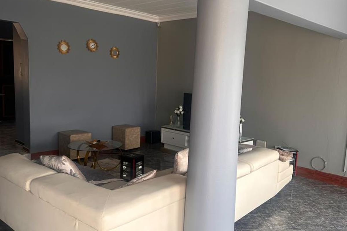 A spacious living area featuring tiled flooring, a prominent structural column, and a coved ceiling, offering a functional layout for relaxation.