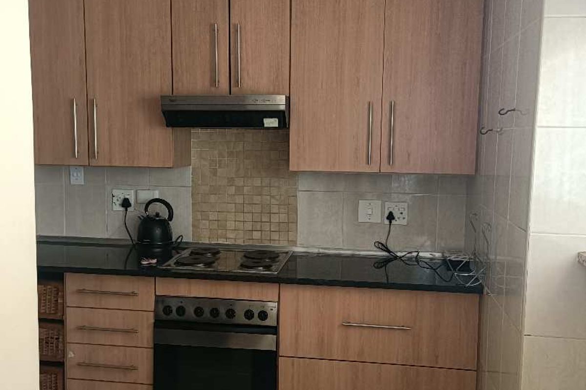 A functional kitchen featuring light wood-finish cabinetry, granite countertops, a mosaic tile backsplash, and integrated stainless steel appliances.