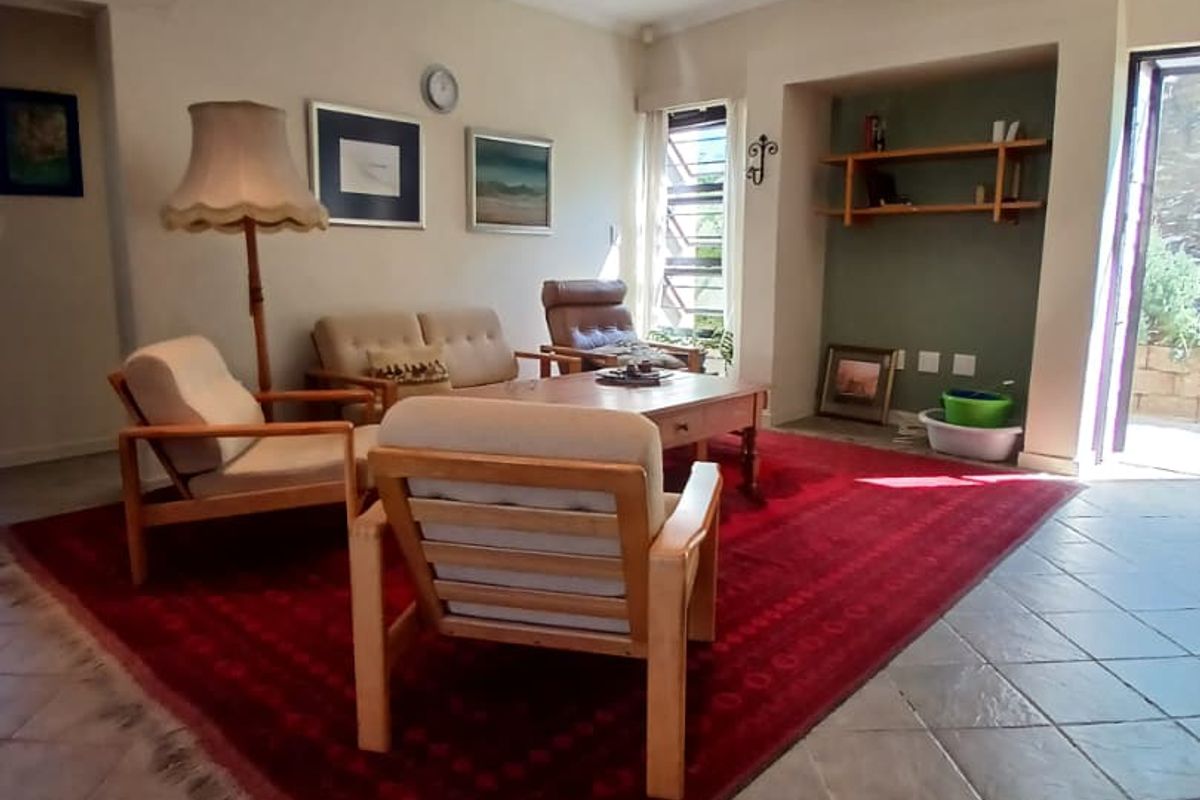 A spacious living room featuring tiled flooring, recessed lighting, and a built-in shelving alcove, with direct access to an outdoor area via a sliding door.