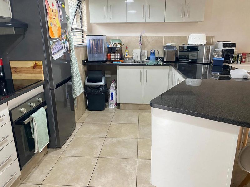 A functional kitchen featuring granite countertops, tiled flooring, built-in oven, extractor fan, and ample upper and lower cabinetry storage.