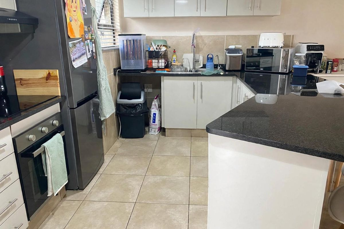 A functional kitchen featuring granite countertops, tiled flooring, built-in oven, extractor fan, and ample upper and lower cabinetry storage.