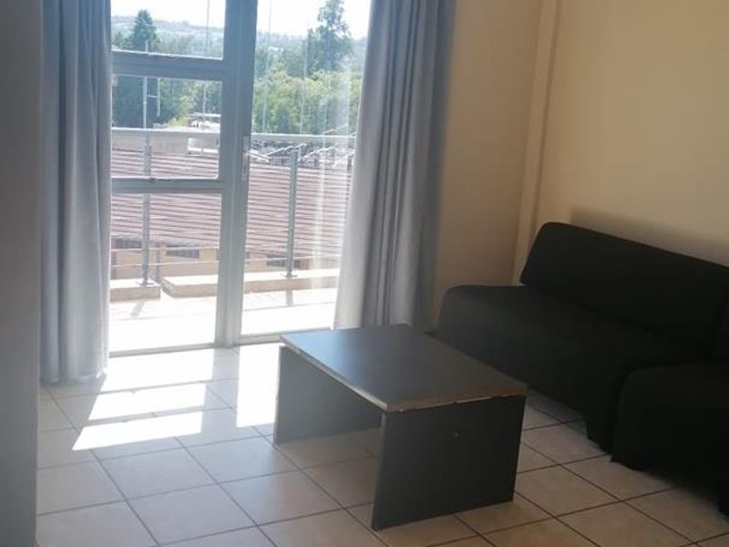 A living room area featuring tiled flooring and a sliding glass door providing access to an outdoor balcony.