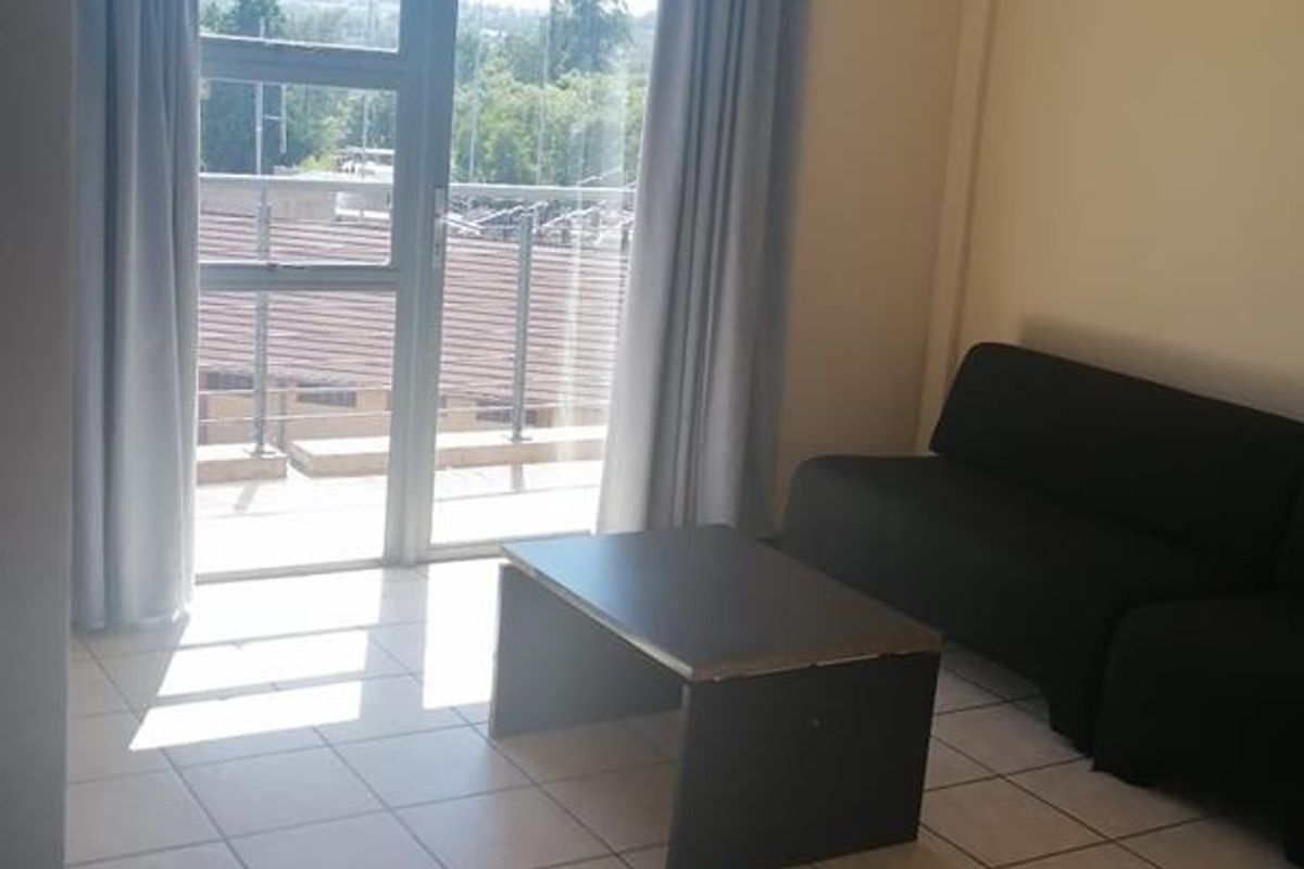 A living room area featuring tiled flooring and a sliding glass door providing access to an outdoor balcony.