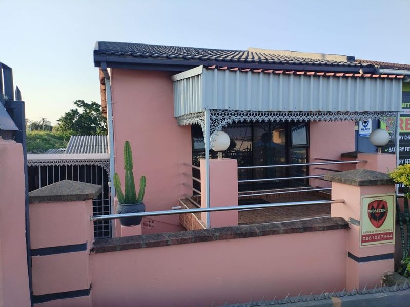 Front exterior view of a house featuring a covered veranda with decorative metal fretwork, stainless steel balustrades, and a tiled roof.