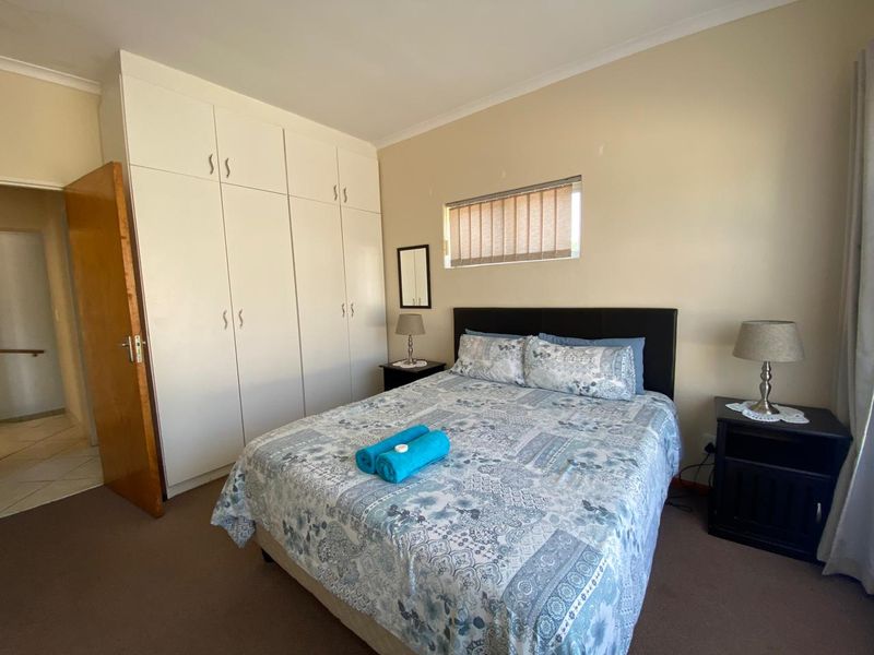 A functional bedroom featuring built-in cupboards, neutral wall finishes, and a high-level window with fitted blinds.