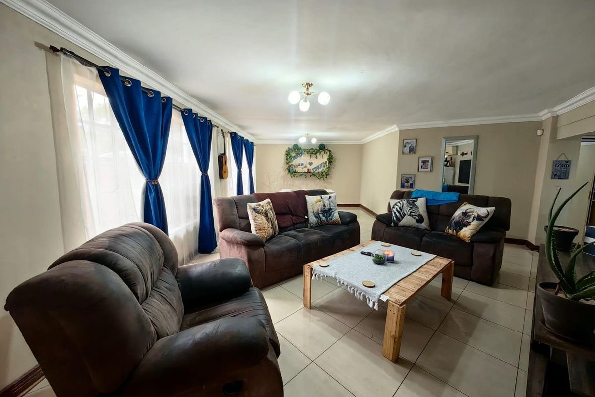 A spacious living room featuring neutral wall tones, tiled flooring, and decorative ceiling coving, offering a comfortable and well-lit area for relaxation.