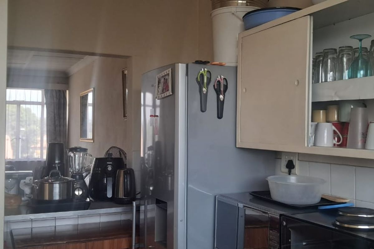 A compact kitchen area featuring built-in cabinetry, tiled splashbacks, and a functional layout with a serving hatch opening into the adjacent living space.