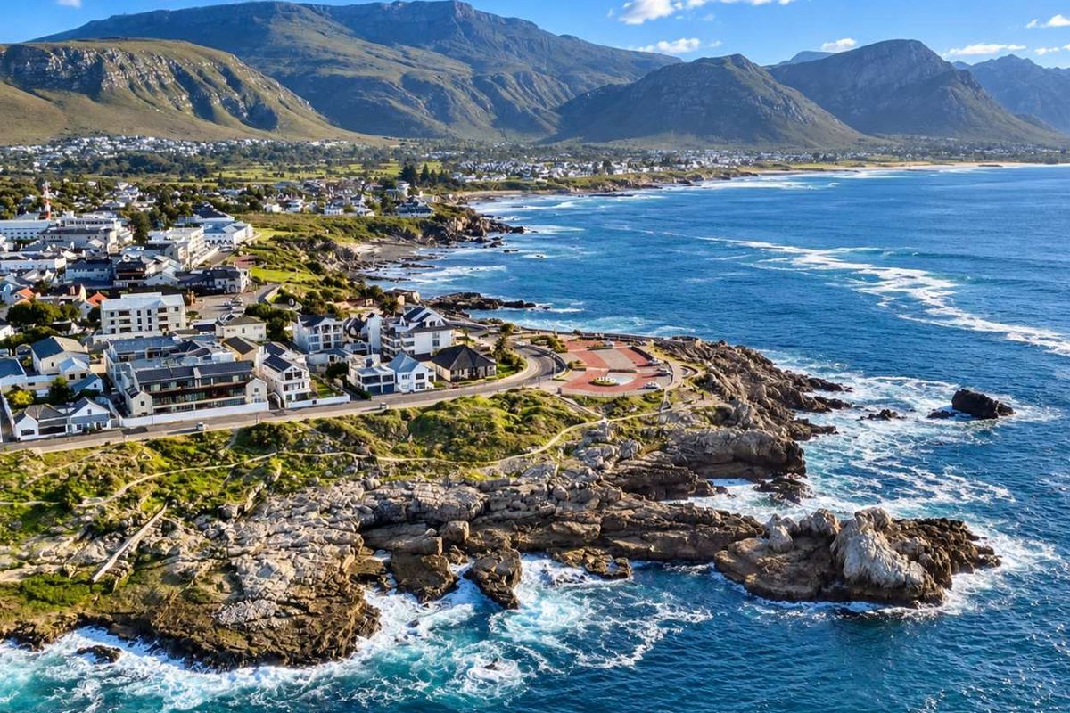 An aerial view of the coastal town and surrounding landscape, showcasing the proximity to the ocean and mountain range.