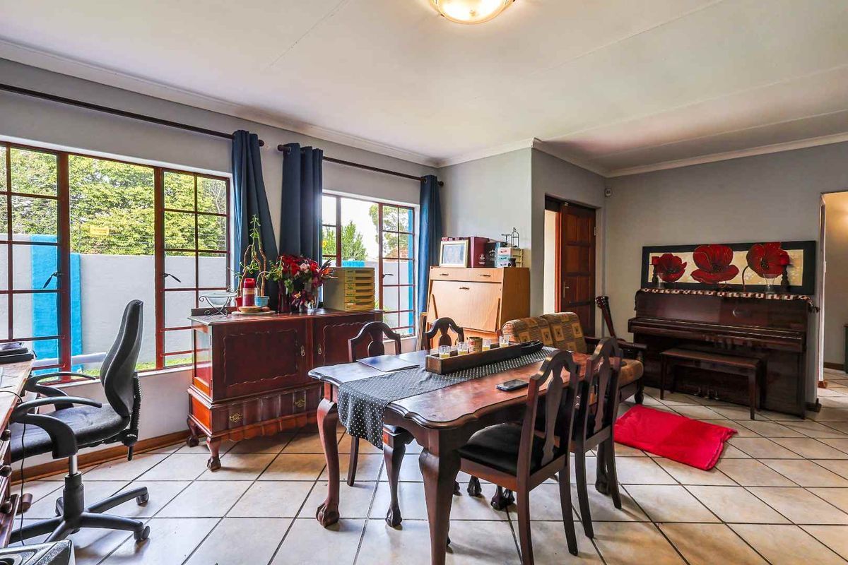 A spacious living and dining area featuring large windows, tiled flooring, and neutral wall finishes, offering a versatile layout for family living.