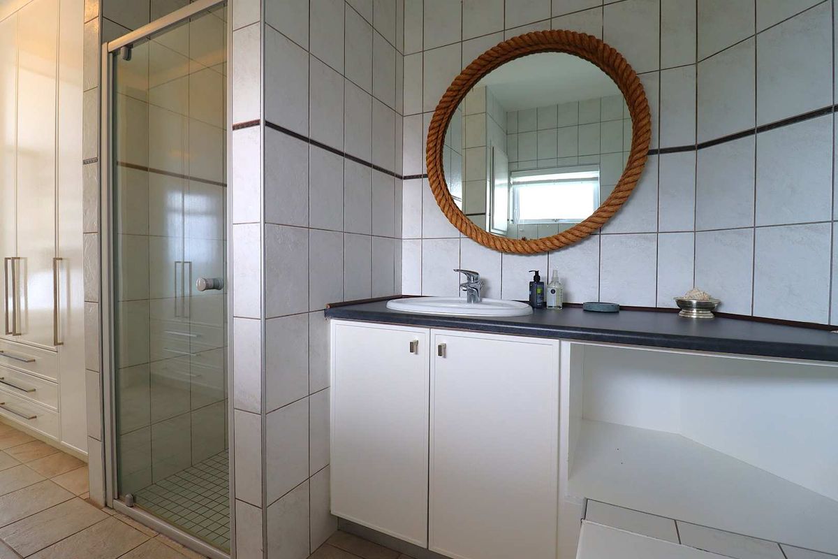 A functional bathroom featuring a glass-enclosed shower, a vanity unit with a basin, and tiled finishes throughout.