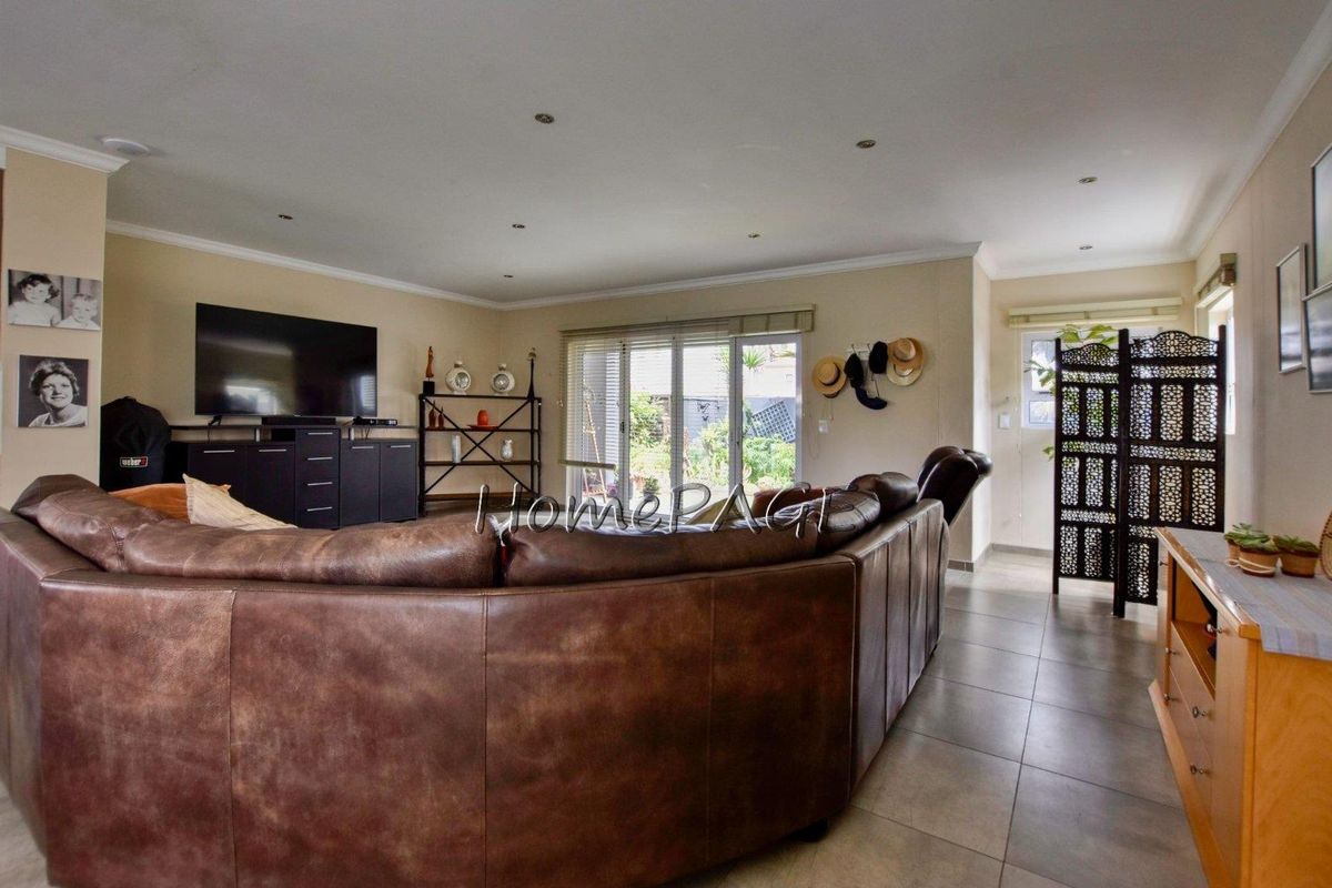 Spacious living room featuring tiled flooring, recessed downlighting, and large sliding glass doors providing direct access to the outdoor area.