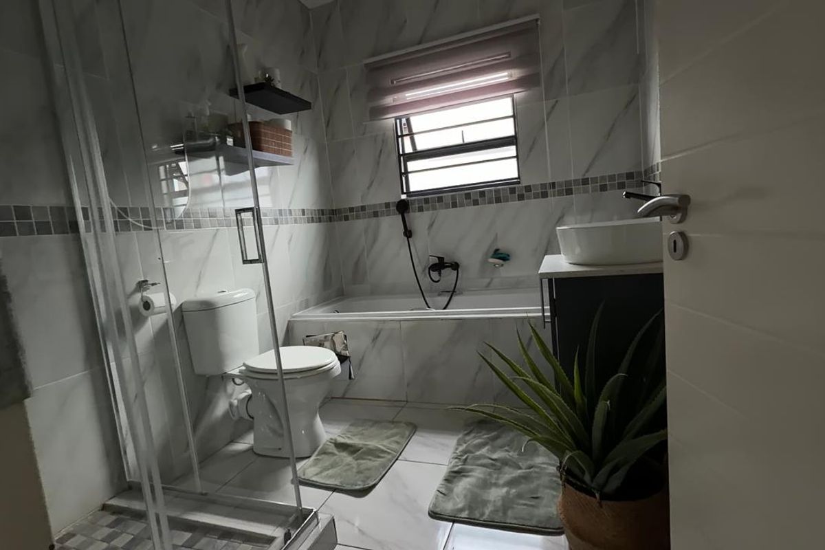 Modern bathroom featuring a glass shower enclosure, built-in bathtub, vanity with vessel sink, and marble-look wall tiling.