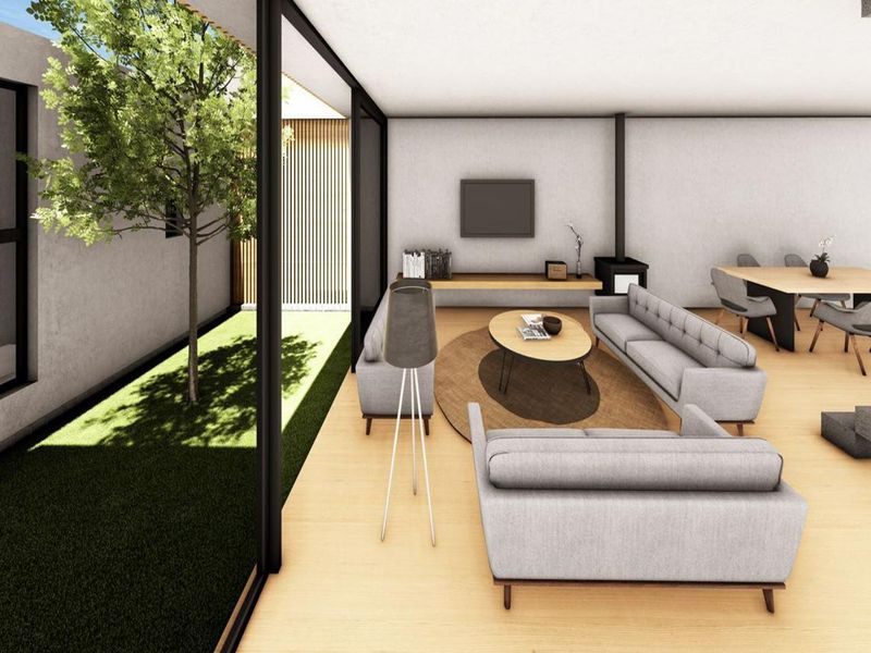 Modern open-plan living and dining area featuring timber flooring, a wood-burning fireplace, and expansive floor-to-ceiling glass doors opening to a private garden courtyard.