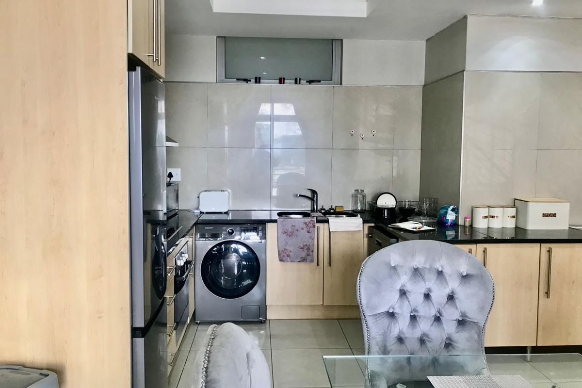 A functional kitchen featuring light wood cabinetry, granite countertops, tiled backsplash, and integrated appliances, including a built-in oven and hob.