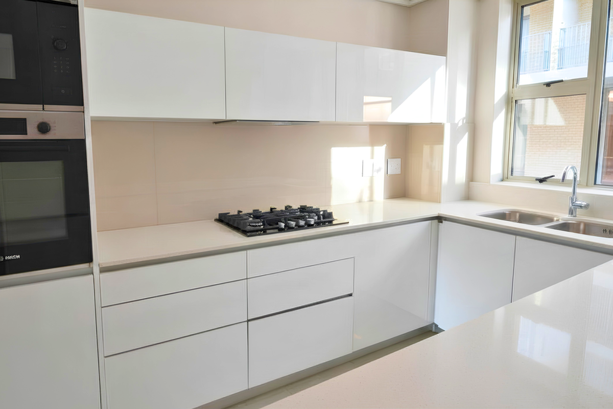 Modern kitchen featuring sleek white glossy cabinetry, stone countertops, integrated Bosch appliances, a gas hob, and a double bowl sink with a window view.