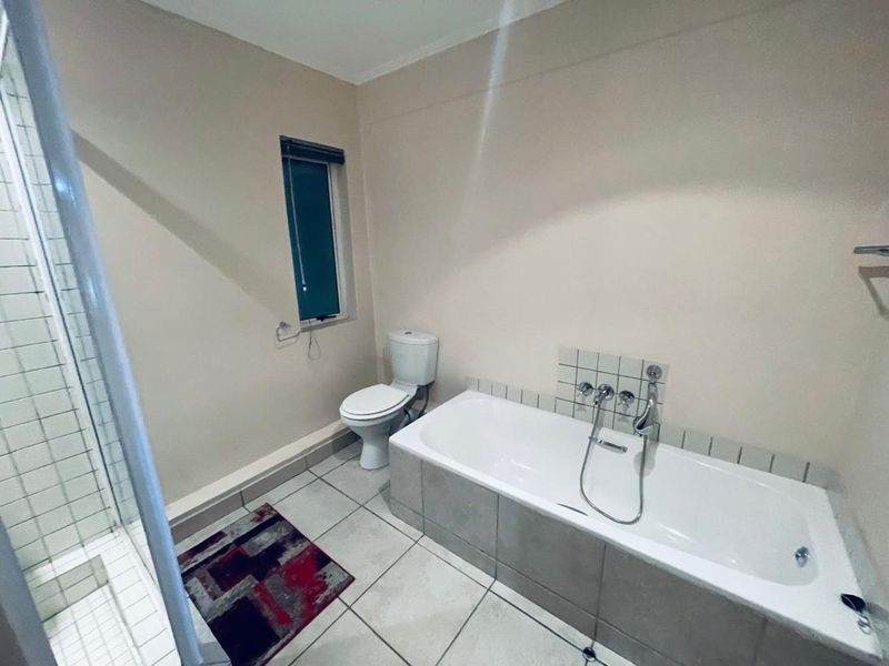 A functional bathroom featuring a bathtub with a shower mixer, a separate shower enclosure, and tiled flooring.