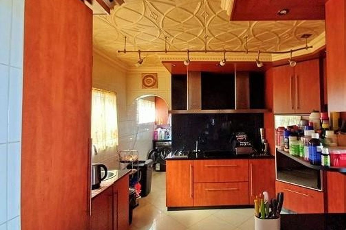 A kitchen featuring wood-toned cabinetry, a decorative ceiling, integrated appliances, and tiled flooring, offering a functional layout with ample storage space.