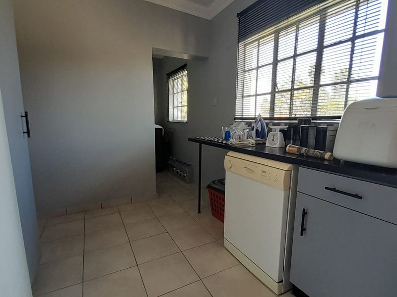 A functional laundry area featuring tiled flooring, built-in cabinetry, and an integrated dishwasher, providing practical utility space for household tasks.