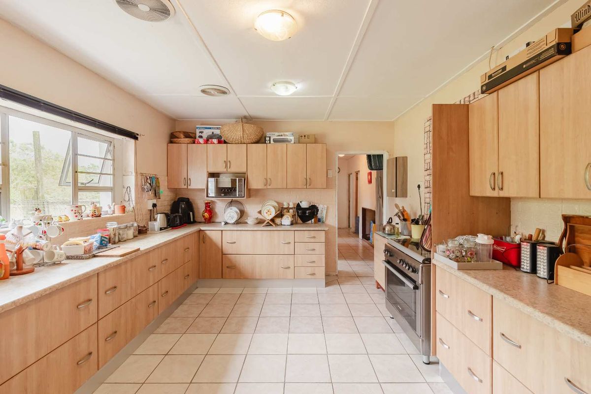 A functional kitchen featuring light wood-tone cabinetry, laminate countertops, tiled flooring, and a freestanding stove, offering a practical layout with ample storage space.