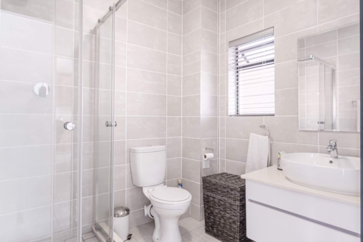 A modern, well-maintained bathroom featuring a glass-enclosed shower, a contemporary vanity with a vessel sink, and neutral wall tiling.