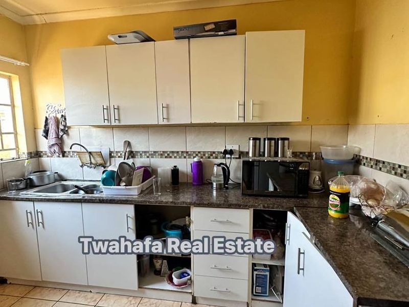 A functional kitchen featuring laminate countertops, tiled backsplash, and built-in cabinetry, currently showing signs of wear and requiring maintenance or cosmetic updates.